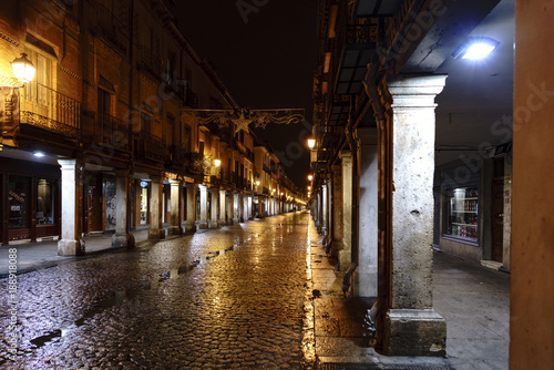 Alcala de Henares, Madrid, Spain. November 28, 2017: Main street of the town called "Mayor" on a cold and rainy night. Without people walking and with light reflections on wet cobblestones
