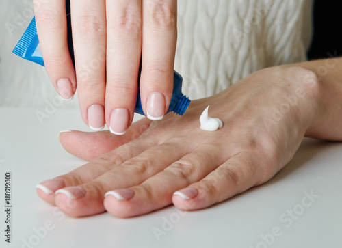 Beautiful woman s hands applying cream