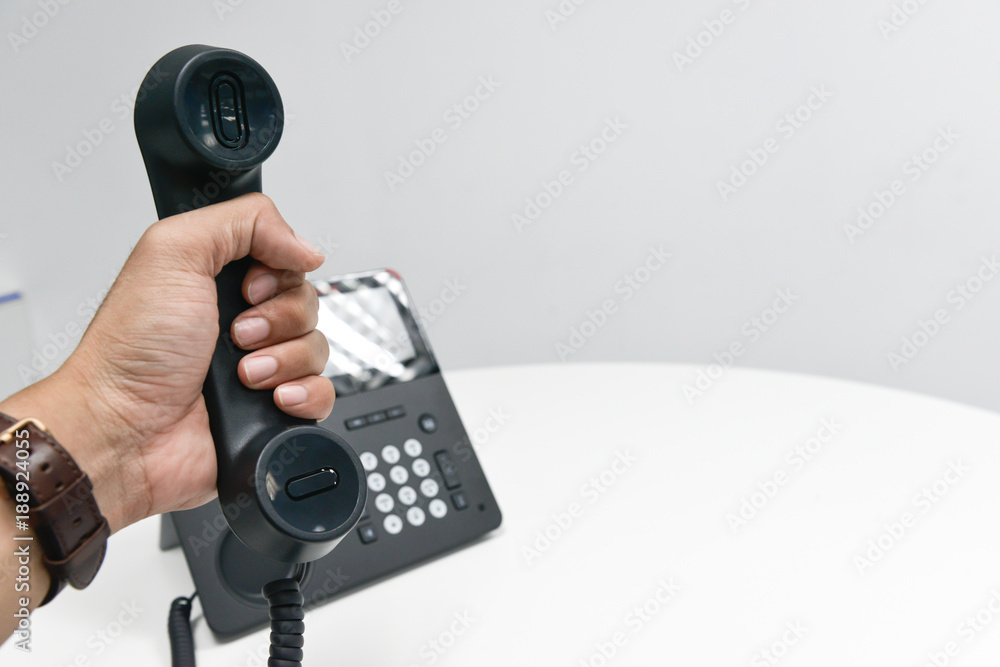 Man business hand is holding the phone hand set answer the office phone