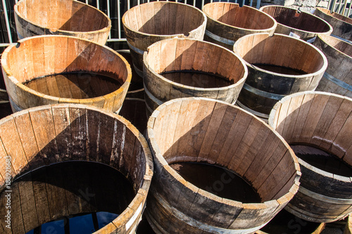 Stacked old wooden half barrels at gerden store is about to have second life as a flower planters or garden decoration.