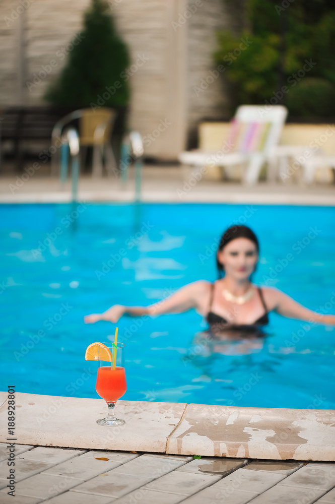 Portrait of beautiful tanned woman in black swimwear relaxing in swimming pool spa.