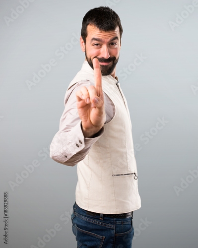 Handsome man with vest counting one on grey background