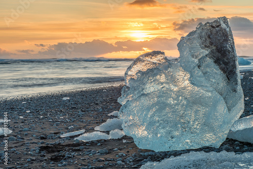 The sun rises over the Atlantic Ocean illuminating the famous Icebergs on Diamond Beach, at the opening of Jökulsárlón glacier lagoon