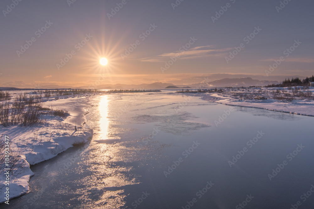 The low sun reflected off the icy waters of Þingvallavatn, Thingvallavatn Lake in Þingvellir National Park in Iceland.