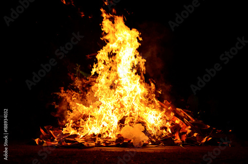 Crest of flame on burning wood in fireplace. Great ritual bonfire on a black background