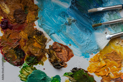 Close-up of artist brushes and colored paints on a white palette
