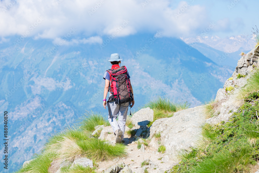 Backpacker walking on hiking trail in the mountain. Summer adventures summer vacation on the Alps. Wanderlust people traveling concept.