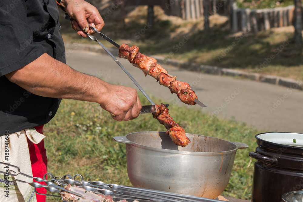 Fototapeta premium barbeque grill, skewers with meat, brazier, cauldron, chef controls willingness dishes