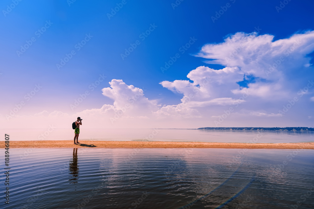 traveler photographer with backpack taking pictures of the sea at rest traveler photographer with backpack taking pictures of the sea at rest