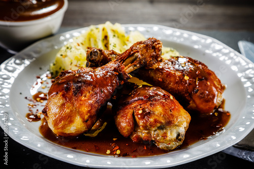 Grilled chicken legs with boiled potatoes on wooden background