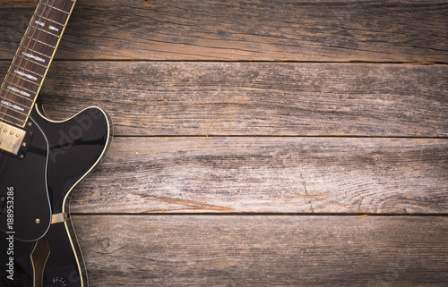 Black electric guitar on a rustic wooden background