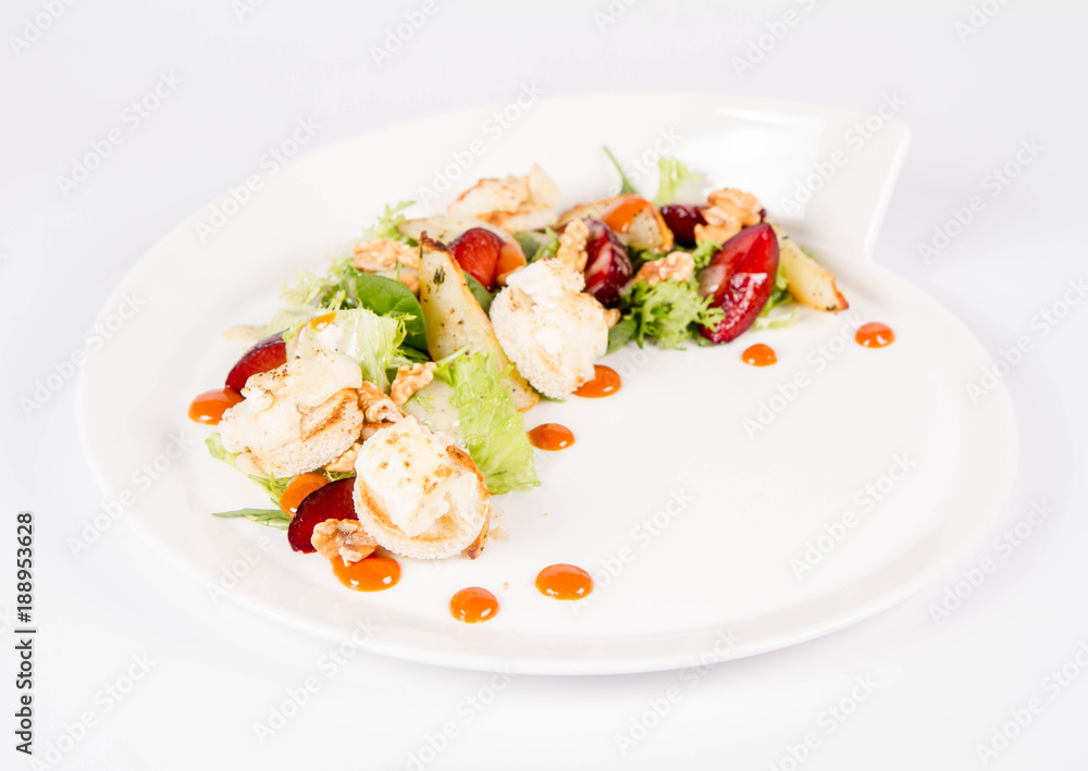 Starter: Mix salads, baked goat cheese, sea-buckthorn jam, caramelized pear with thyme, plum and roast nuts - on a white background Starter: Mix salads, baked goat cheese, sea-buckthorn jam, caramelized pear with thyme, plum and roast nuts - on a white background