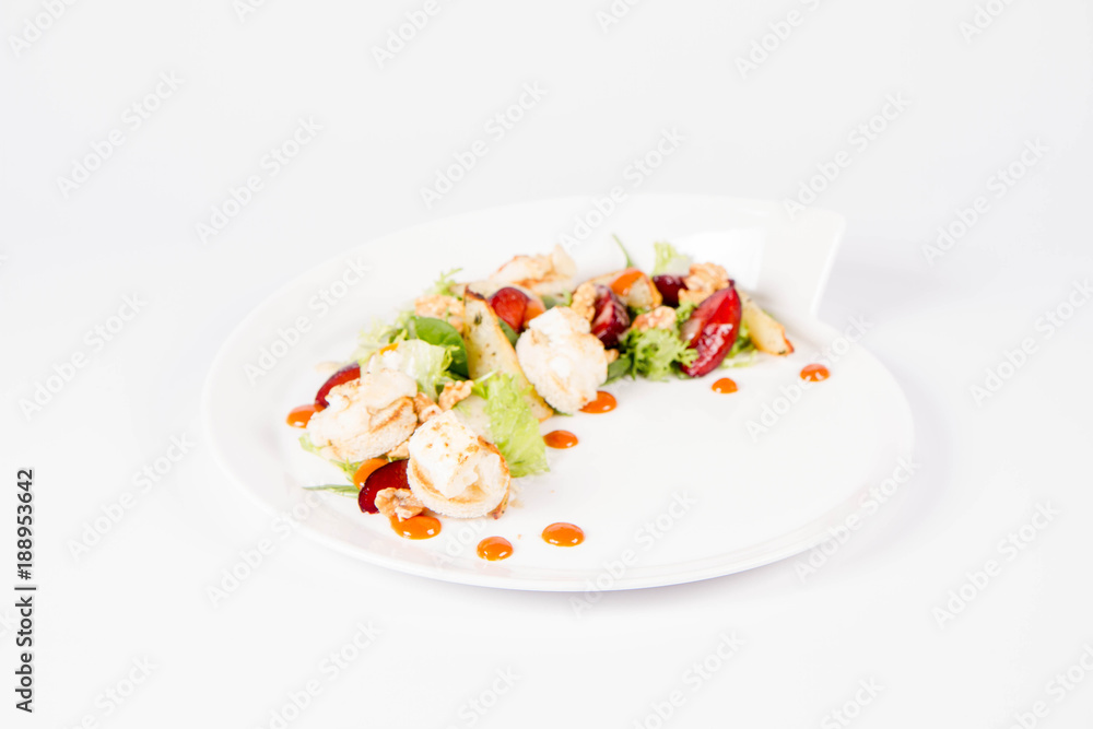 Starter: Mix salads, baked goat cheese, sea-buckthorn jam, caramelized pear with thyme, plum and roast nuts - on a white background Starter: Mix salads, baked goat cheese, sea-buckthorn jam, caramelized pear with thyme, plum and roast nuts - on a white background