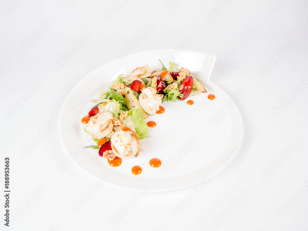 Starter: Mix salads, baked goat cheese, sea-buckthorn jam, caramelized pear with thyme, plum and roast nuts - on a white background Starter: Mix salads, baked goat cheese, sea-buckthorn jam, caramelized pear with thyme, plum and roast nuts - on a white background