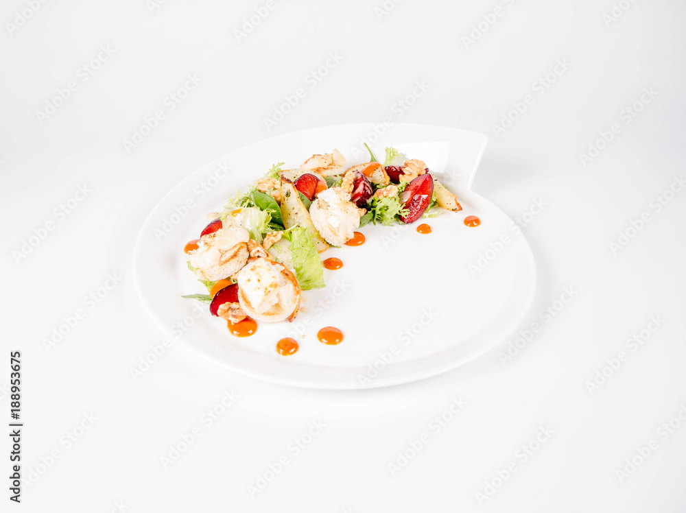 Starter: Mix salads, baked goat cheese, sea-buckthorn jam, caramelized pear with thyme, plum and roast nuts - on a white background Starter: Mix salads, baked goat cheese, sea-buckthorn jam, caramelized pear with thyme, plum and roast nuts - on a white background