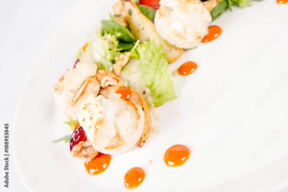 Starter: Mix salads, baked goat cheese, sea-buckthorn jam, caramelized pear with thyme, plum and roast nuts - on a white background Starter: Mix salads, baked goat cheese, sea-buckthorn jam, caramelized pear with thyme, plum and roast nuts - on a white background