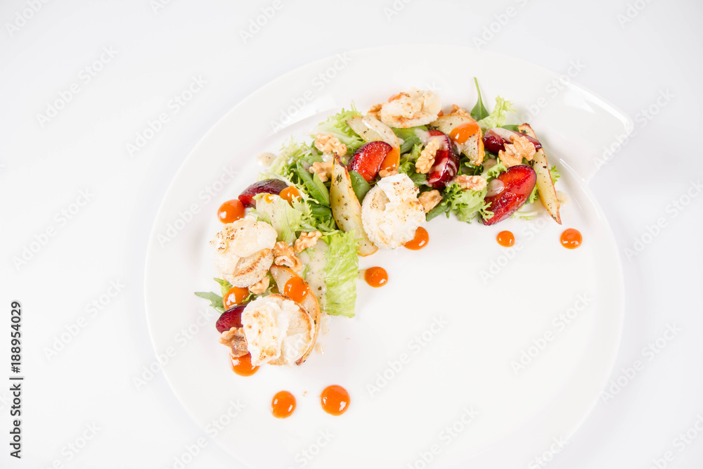 Starter: Mix salads, baked goat cheese, sea-buckthorn jam, caramelized pear with thyme, plum and roast nuts - on a white background Starter: Mix salads, baked goat cheese, sea-buckthorn jam, caramelized pear with thyme, plum and roast nuts - on a white background