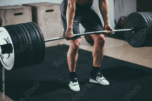 Muscular fitness man doing deadlift barbell in modern fitness center.Functional training photo