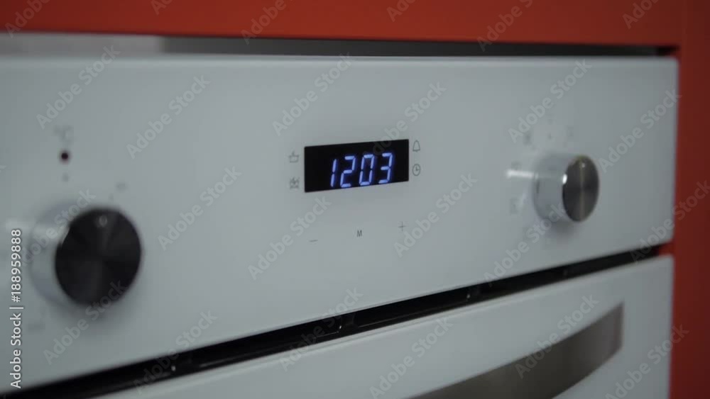 Metallic Toggle Switch of the Cooker Oven. Close-up View. Digital Clock of oven. Front panel of modern white glass oven, red indicators, new shiny buttons. Modern design in details. Metallic Toggle Switch of the Cooker Oven. Close-up View. Digital Clock of oven. Front panel of modern white glass oven, red indicators, new shiny buttons. Modern design in details.