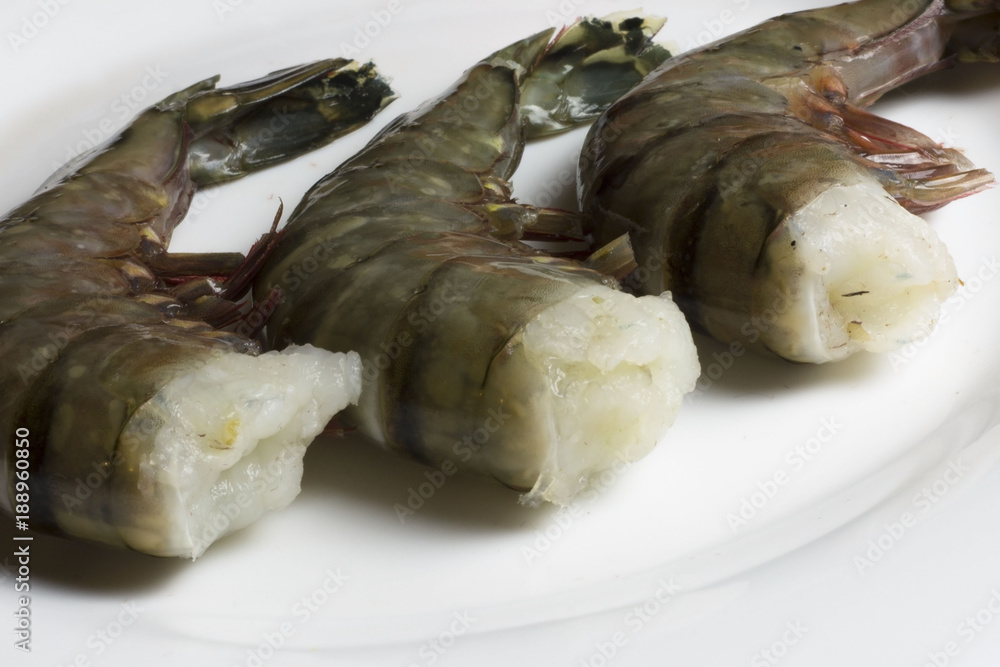 Fresh, raw, uncooked headless tiger prawns. Sea shrimps on white background. Fresh, raw, uncooked headless tiger prawns. Sea shrimps on white background.