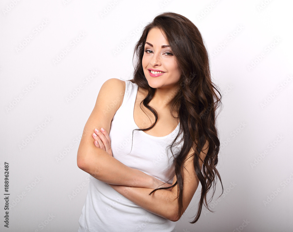 Beautiful positive young casual woman with folded arms in white shirt and long hair toothy smile. Beautiful positive young casual woman with folded arms in white shirt and long hair toothy smile.