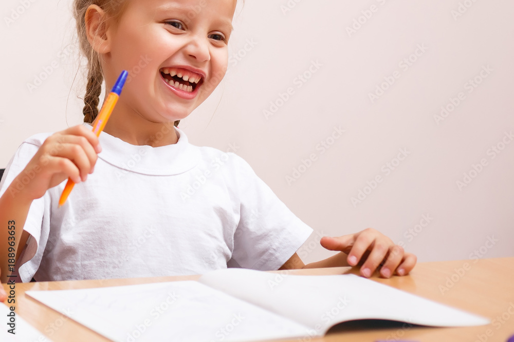 Two happy girls sit at wooden school desk in classroom at school. Two happy girls sit at wooden school desk in classroom at school.