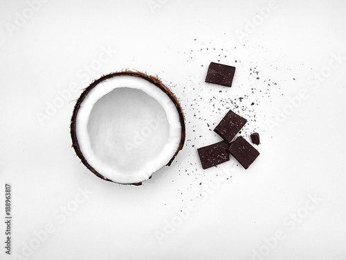 Coconut Flat lay Half coconut in peel and broken chocolate bars are lying on white background Top view Trendy colorful photo mockup with space for text