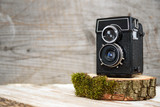 Old vintage camera on wooden stand, wooden background, retro theme, auctions and hobbies