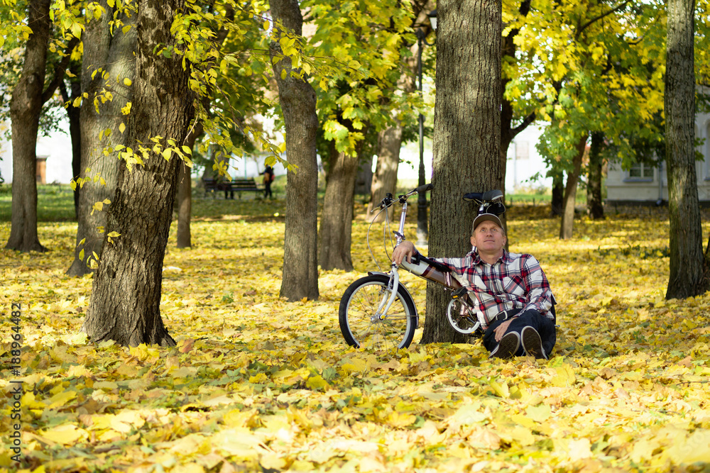 Senior and his bicycle in autumn park.