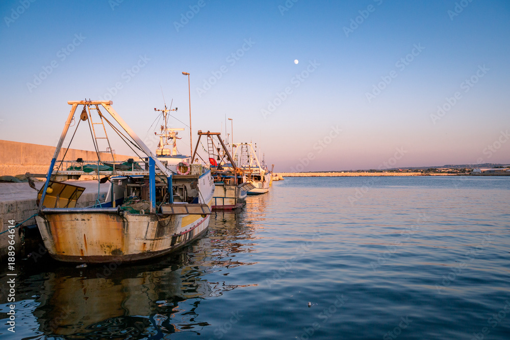 Sunset over trawler fishing boat docket in harbour. Apulia, Italy