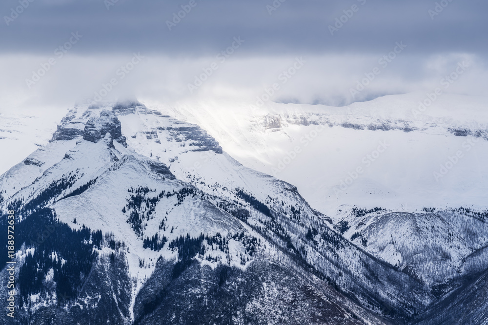 Storm clouds moving in over snow covered mountains