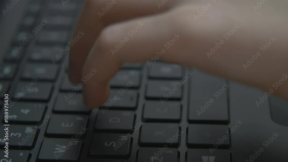 The hands of a large child works on the keyboard. Boy typing text on laptop The hands of a large child works on the keyboard. Boy typing text on laptop