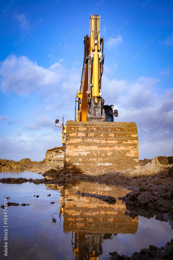 Schlechtwetterphase in der Baubranche - Bagger steht im Schlamm, Hochformat Schlechtwetterphase in der Baubranche - Bagger steht im Schlamm, Hochformat