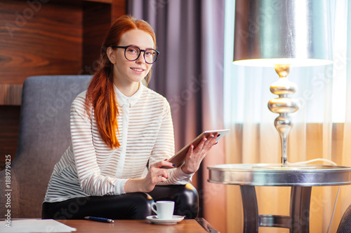 Foto Beautiful redhead young woman holding digital tablet and looking at camera with