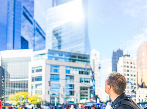 Closeup of young man's head back looking up at skyscrapers in New York City NYC Columbus Circle on sunny day photo