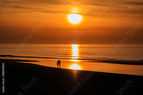 Liebespaar schaut in die untergehende rote Sonne