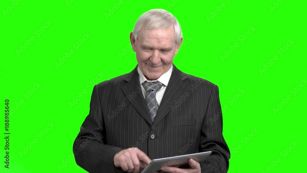 Senior grandpa use tablet. Old man in suit using tablet and looks up to the camera, green hromakey background. Senior grandpa use tablet. Old man in suit using tablet and looks up to the camera, green hromakey background.