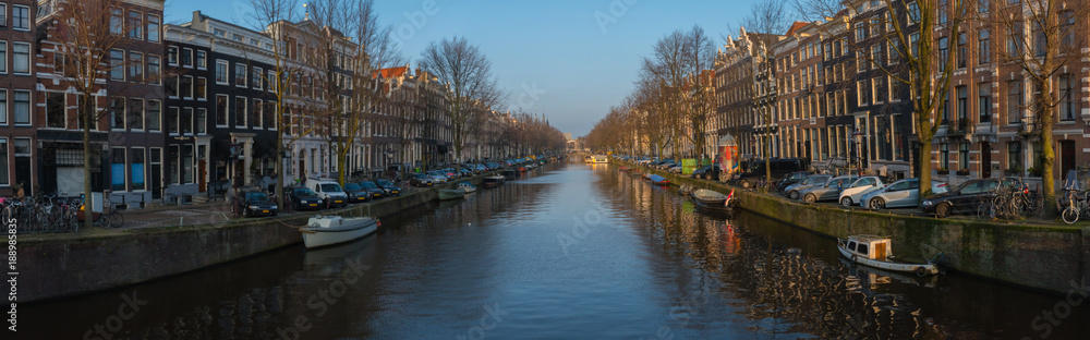 Panorama of Amsterdam canal. Typical dutch houses, bridge and houseboats. Holland, Netherlands. Pretty dutch doll houses reflected in the tranquil canals of Amsterdam.