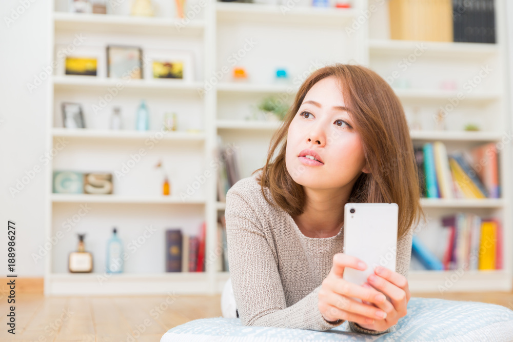 部屋でスマホを見る女性 考える 部屋でスマホを見る女性 考える