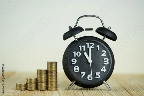 Steps of coins stack with vintage alarm clock on wooden working table with copy space for text, financial and business planning concept.