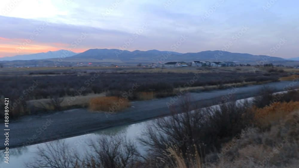 Panorama of a river at dusk with a sunset beyond the distant mountains Panorama of a river at dusk with a sunset beyond the distant mountains