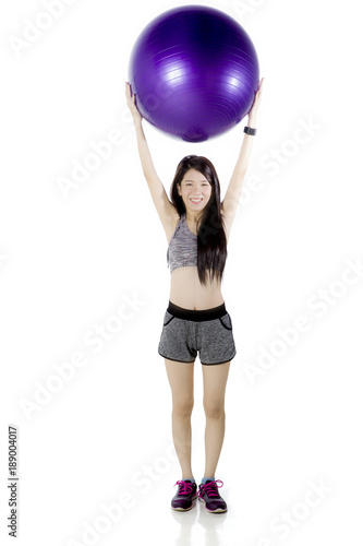 Chinese woman lifting a fitness ball on studio