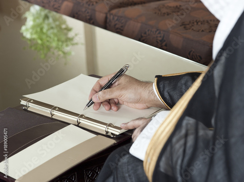 Saudi Arabian Man Hand Writing on A Notebook photo