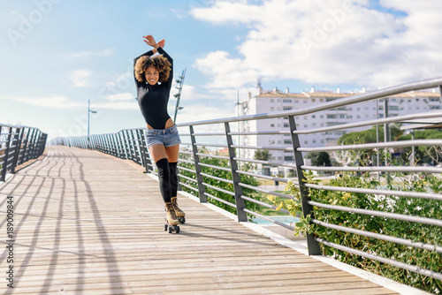 Afro hairstyle woman on roller skates riding outdoors on urban bridge © javiindy