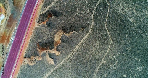 Surreal landscape with red road and hiking paths. Aerial view on sandstone hills covered with sparse vegetation with road and hiking paths creating unique pattern. photo