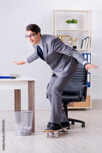 Young businessman riding skate in office during break