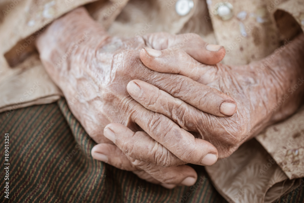 Fototapeta premium Hands Asian elderly woman grasps her hand on lap, pair of elderly wrinkled hands in prayer sitting alone in his house, World Kindness older and Adult care, Mother day people concept