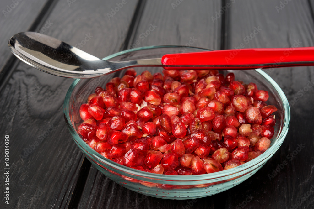 group of pomegranate grains in glass bowl on black wood group of pomegranate grains in glass bowl on black wood