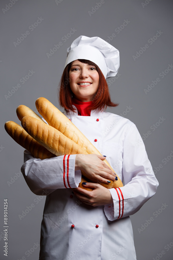 Image of cook girl in white dressing gown and cap with baguettes Image of cook girl in white dressing gown and cap with baguettes