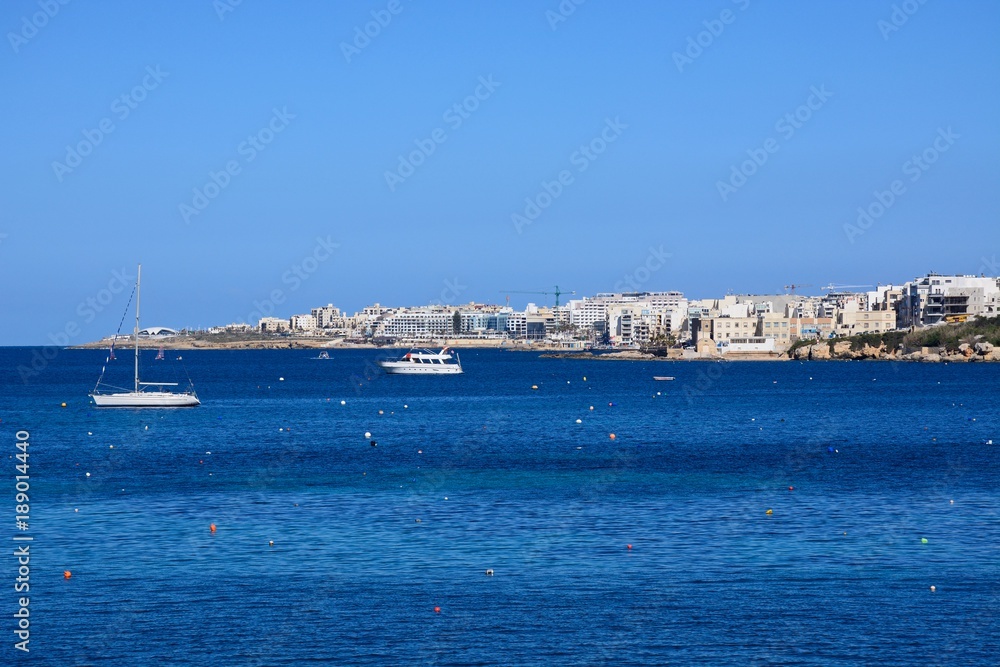 Boats moored in the sea with views towards St Pauls Bay, San Pawl, Malta.